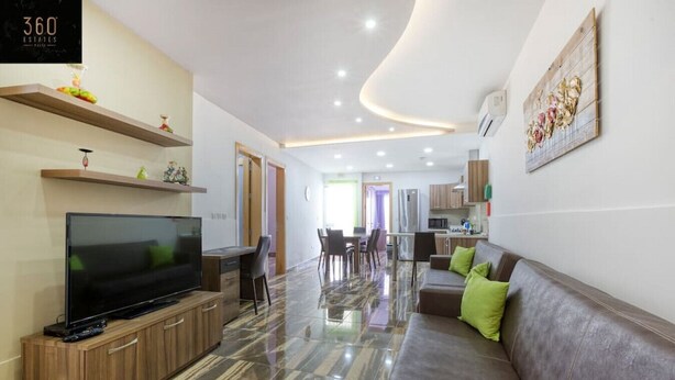 A modern living room with a flat-screen TV, a sofa, and a dining area with chairs and a table. - Central 4BR, massive APT with private POOL & BBQ (Is-Swieqi)