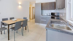 A modern kitchen with grey cabinets, a wooden dining table, and a built-in sink. - Beautiful, stunning 3BR home, opposite the harbour (Tal-Pietà)