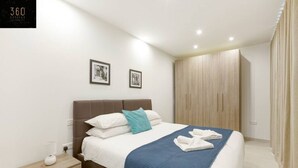 A modern hotel room with a neatly made bed, a bedside table with a lamp, and a wardrobe. - Beautiful, stunning 3BR home, opposite the harbour (Tal-Pietà)