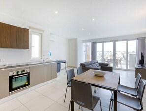 Een modern appartement met keuken, eethoek en balkon met uitzicht op de stad.