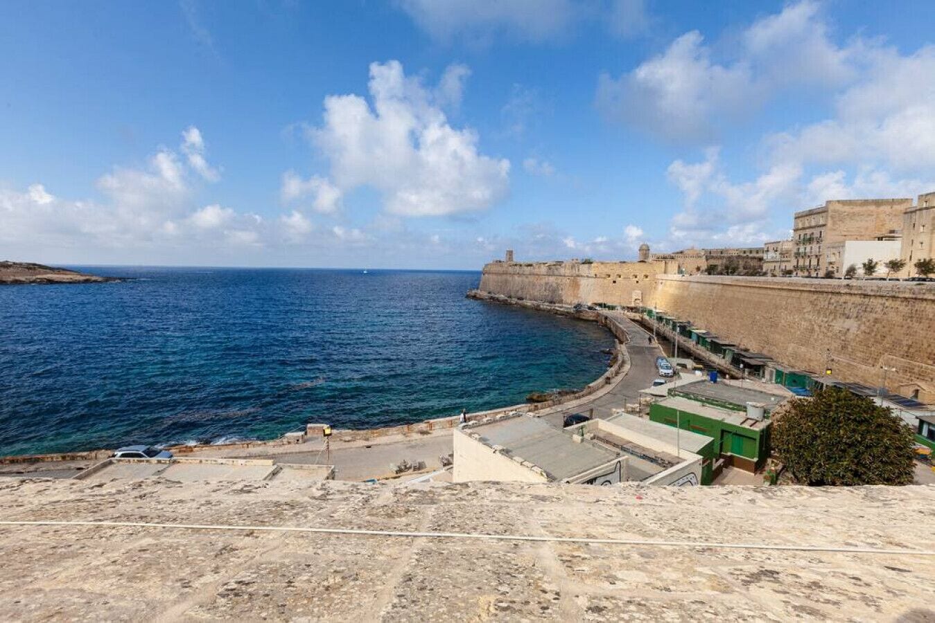 A coastal view with a fortified structure, a clear sky, and a calm sea.