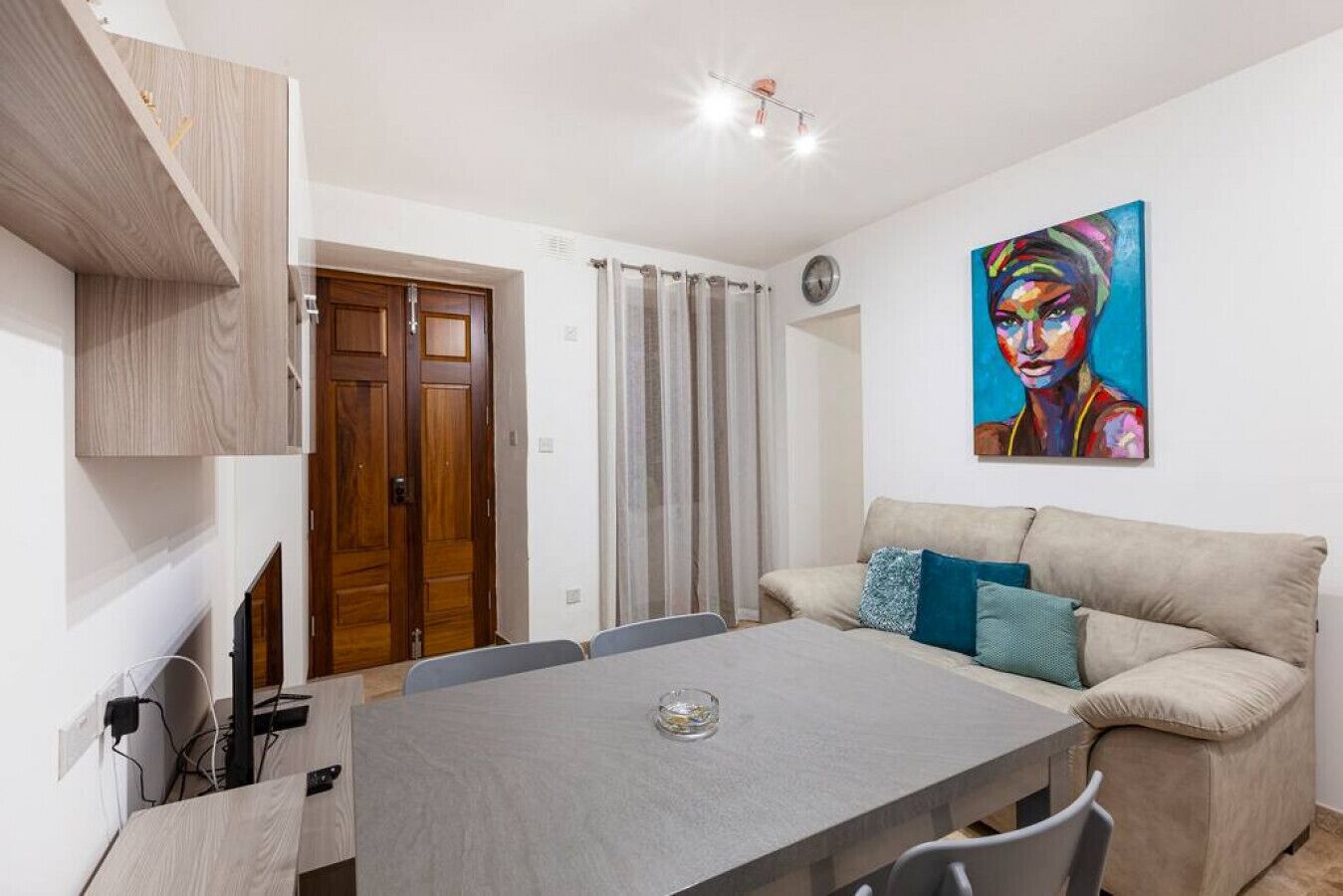 Una sala de estar moderna con una mesa de comedor, un sofá y un cuadro en la pared.
