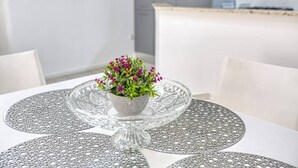 Ein Esstisch mit einer Glas-Vase in der Mitte und einer weißen Tischdecke.
