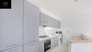 Eine moderne Küche mit grauen Schränken, einem eingebauten Backofen, einer Mikrowelle und einer Waschmaschine.