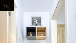 Ein Flur mit weißer Wand, Holzboden und einem weißen Schrank mit Schubladen und Ablagen.