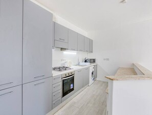 A modern kitchen with grey cabinets, a built-in oven, microwave, and washing machine. - SGN006 · Beautiful & Modern 2BR Apartment in San Gwann (San Ġwann)