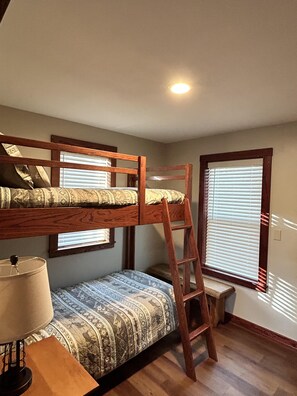 A bunk bed room with a ladder, a desk with a lamp, and a window with blinds. - Fishin' Hole (Cadiz)
