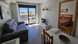 Una sala de estar moderna con un sofá, un televisor y una zona de comedor con una mesa y sillas.