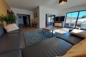 En moderne stue med sofa, et rundt bord og udsigt til det fri.