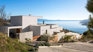 Uma casa moderna com telhado plano, garagem coberta e vista para o mar.