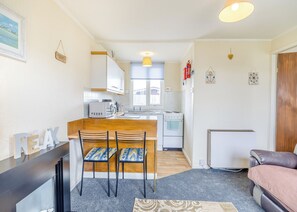 Una cocina compacta con comedor, refrigerador y sofá.