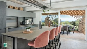 A modern kitchen with a central island, bar stools, and a view of the outdoors. - COZY VILLA FLORA - PRIVATE POOL AND WALKING DISTANCE FROM THE BEACH (San Teodoro)