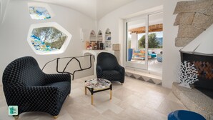 A modern living room with two patterned armchairs, a small round table, and a large window with a view of the outdoors. - COZY VILLA FLORA - PRIVATE POOL AND WALKING DISTANCE FROM THE BEACH (San Teodoro)