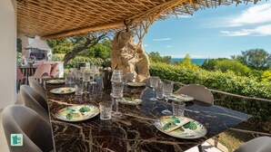 An outdoor dining area with a view of the sea, a pergola overhead, and a rustic stone wall. - COZY VILLA FLORA - PRIVATE POOL AND WALKING DISTANCE FROM THE BEACH (San Teodoro)