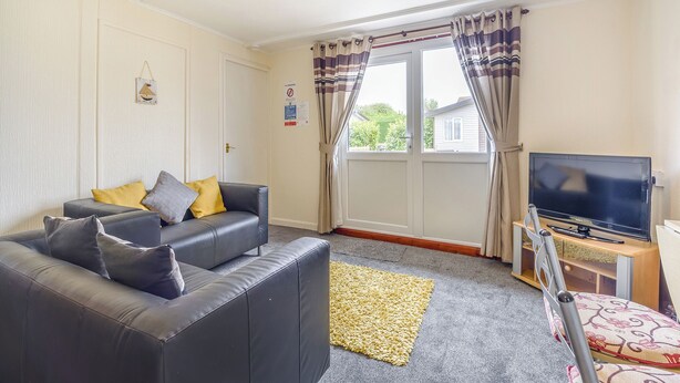 A living room with a sofa, television, and a view through a window. - 1 bedroom accommodation in Anderby Creek, Mablethorpe (Anderby Creek, Mablethorpe)