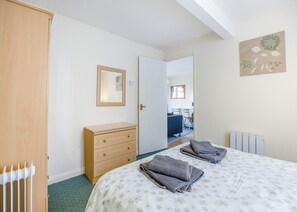 A bedroom with a bed, a wooden dresser, a mirror, and a radiator. - 2 bedroom accommodation in Anderby Creek, Mablethorpe (Anderby Creek, Mablethorpe)