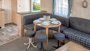 Une pièce chaleureuse avec une table ronde dressée pour quatre personnes, un canapé et une petite kitchenette.