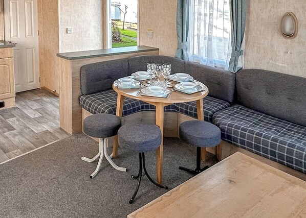 A cozy room with a round table set for four, a sofa, and a small kitchenette.