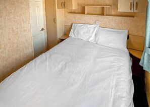 A single bed with white bedding, a wooden headboard, and a wooden nightstand with a lamp.