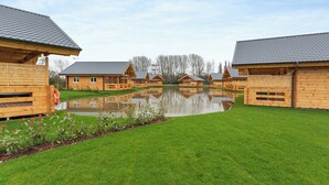 Une rangée de cabanes en bois, avec un étang au premier plan.