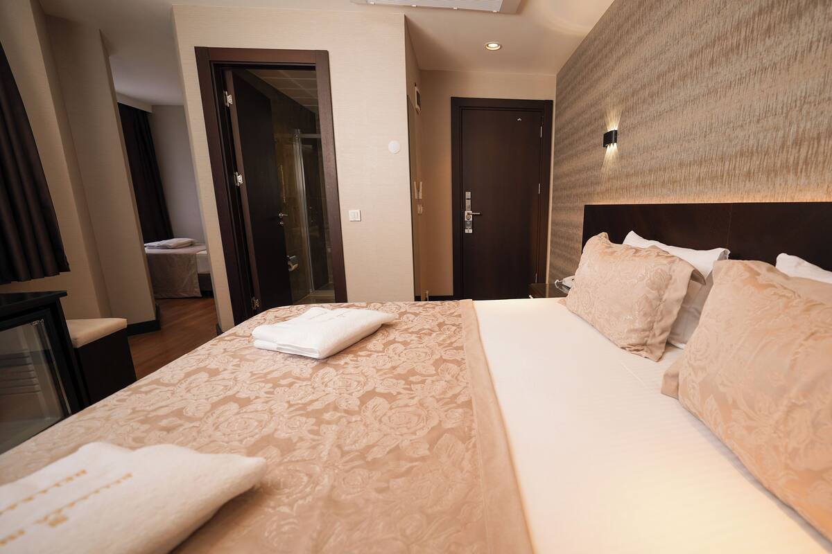 A hotel room with a large bed, a bedside table, a mirror, and a door leading to a bathroom.