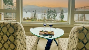 A room with a glass table set for two, a view of mountains, and patterned chairs. - Hilltop Home on Lake Whatcom | Views, Beach Access & Space for Ten (Bellingham)