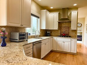 A kitchen with white cabinets, a built-in oven, a dishwasher, and a stove.