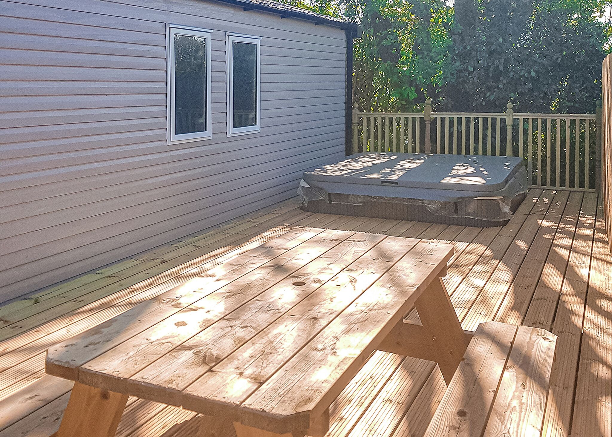 A wooden deck with a picnic table, a small shed, and a wooden fence.
