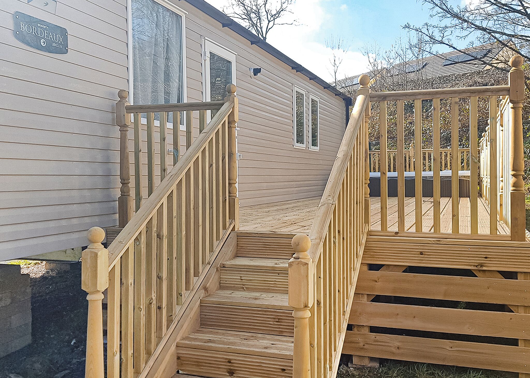 A wooden staircase leading to a deck with a house in the background.