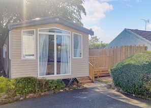A mobile home with a number '53' on the window, a wooden fence, and a paved driveway.