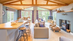 A spacious living area with a wooden ceiling, a fireplace, a television, and a dining area with a wooden table and chairs. - 2 bedroom accommodation in Lauder (Lauder)