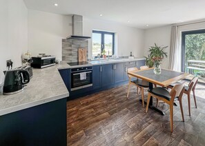 Eine moderne Küche mit Kochinsel, integriertem Backofen und einem Essbereich mit Tisch und Stühlen.