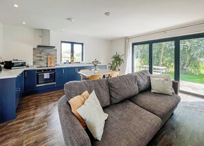 Eine moderne Küche mit blauen Schränken, einem eingebauten Backofen und einem Essbereich mit Tisch und Stühlen.