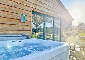 Eine Holzhütte mit Whirlpool, einer Glastür, die auf eine Terrasse führt, und einem Schild an der Wand.