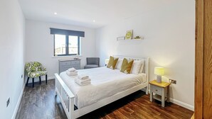 A bedroom with a bed, bedside table, chair, and a window. - 1 bedroom accommodation in Old Buckenham (Old Buckenham)