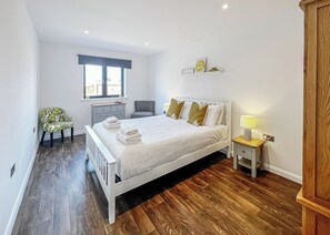 A bedroom with a bed, bedside table, chair, and a window.
