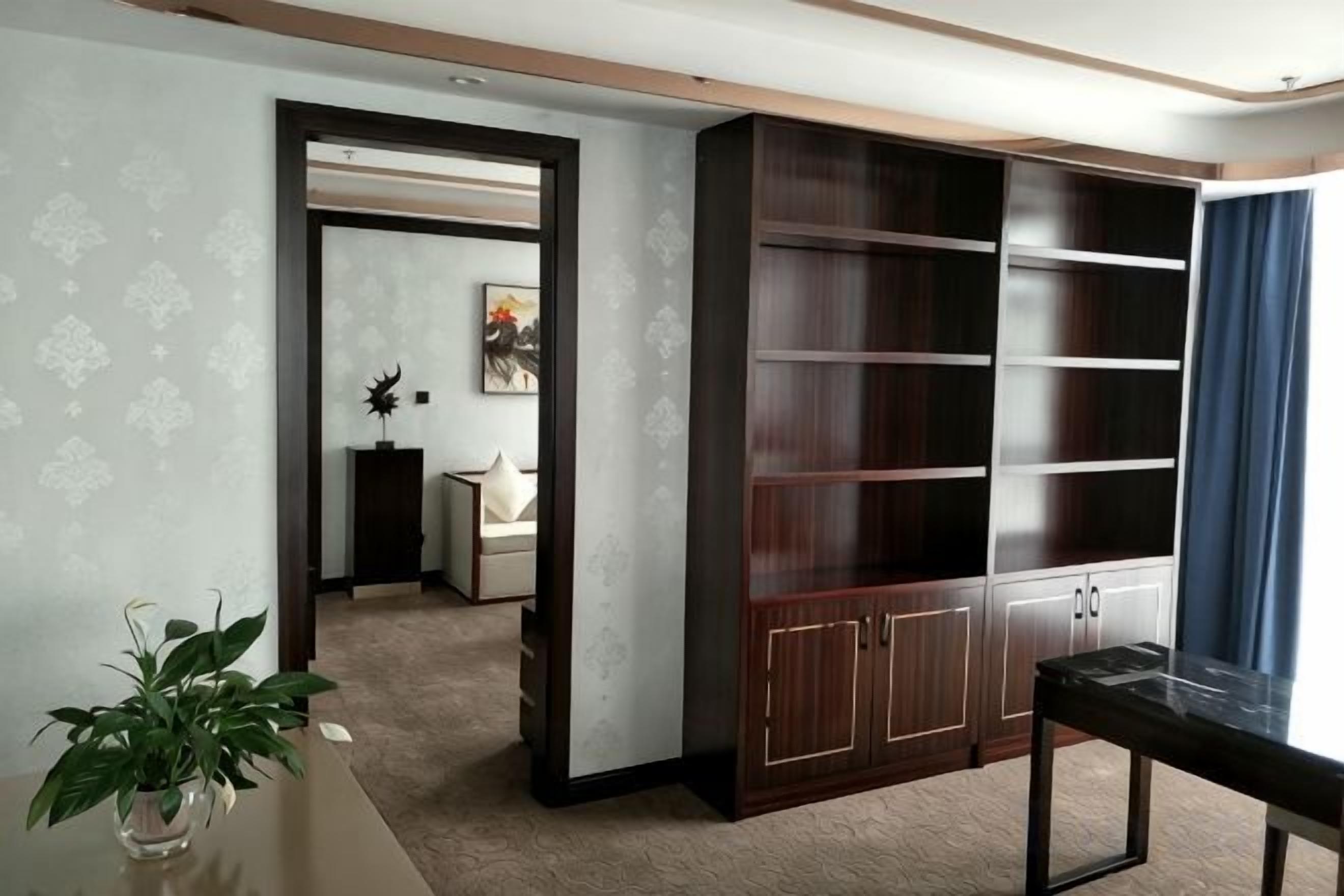 A room with a large wooden cabinet, a small table, and a potted plant.