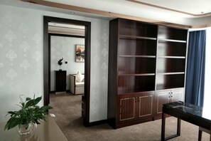 A room with a large wooden cabinet, a small table, and a potted plant. - Bohao Hotel (Zunyi)