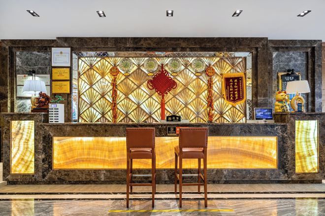 A reception desk with two chairs, a decorative wall with traditional patterns, and a plaque.