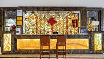 A reception desk with two chairs, a decorative wall with traditional patterns, and a plaque.