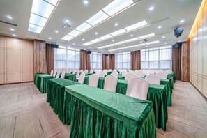 A conference room with rows of tables, chairs, and a wooden floor. - Bohao Hotel (Zunyi)