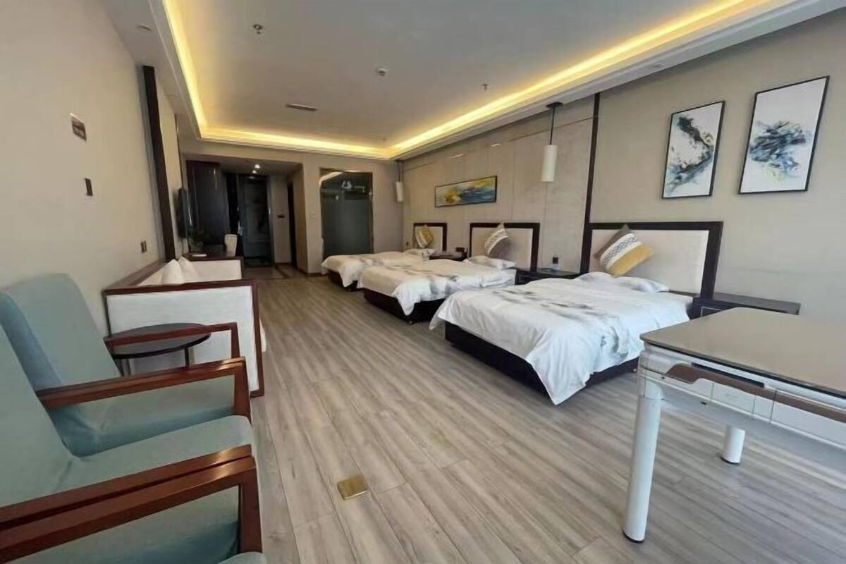 A hotel room with two beds, a desk, a chair, and a small table.