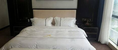 Una habitación de hotel con una cama grande, una mesita de noche y un cuadro en la pared.