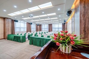 A conference room with multiple tables, a wooden reception desk, and a vase of flowers.