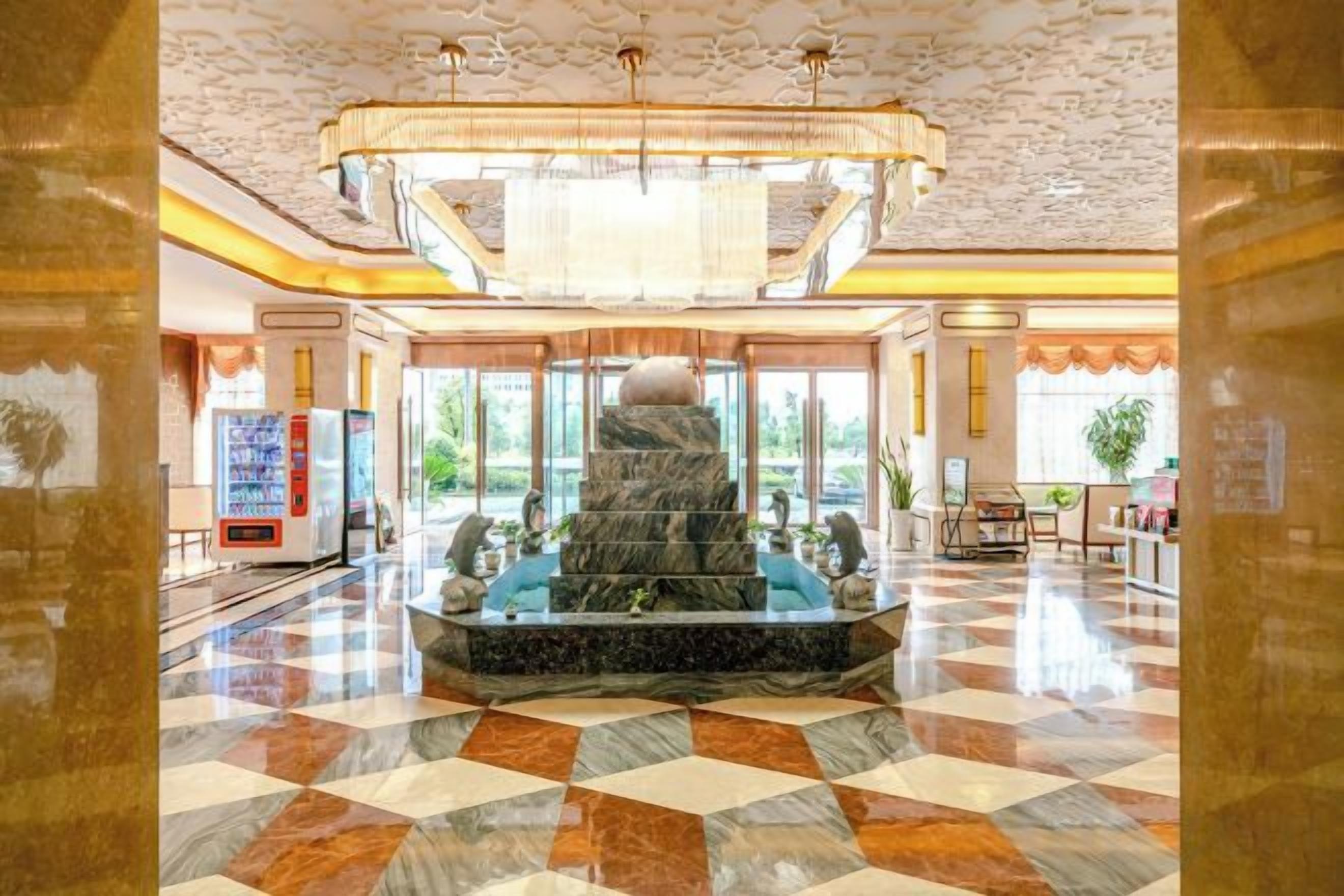 A lobby with a marble fountain, a vending machine, and a reception desk.