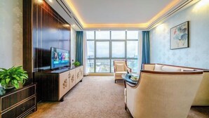 A modern living room with a flat-screen TV, a sofa, a dining table, and a large window. - Bohao Hotel (Zunyi)