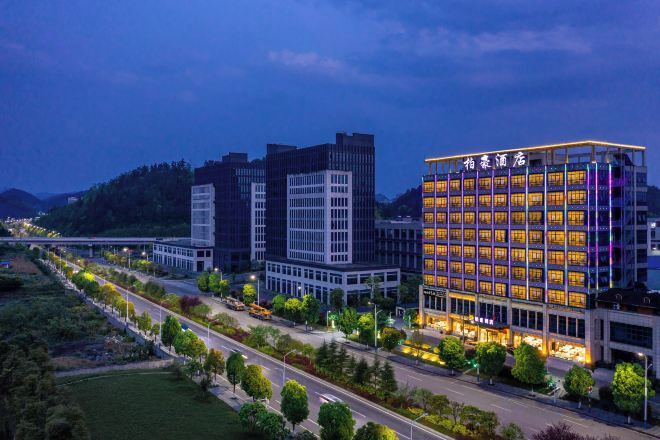 Een modern hotel met meerdere verdiepingen, een goed verlichte gevel en een aangelegde omgeving.