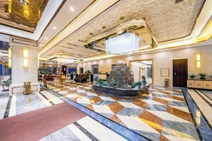 A spacious lobby with a checkered floor, a central fountain, and a chandelier. - Bohao Hotel (Zunyi)