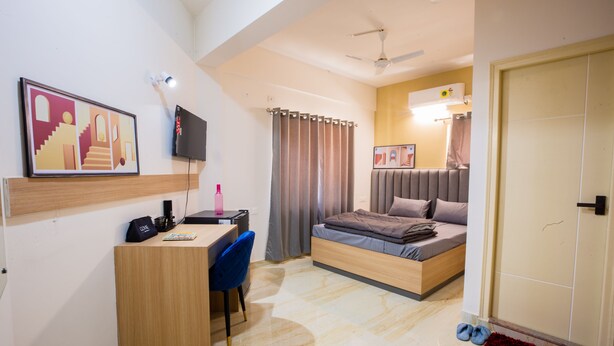 A compact bedroom with a bed, desk, chair, and a TV. - Covie Karle Town 220 (Bengaluru)