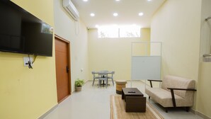 A modern living room with a flat-screen TV, a sofa, a coffee table, and a dining area with chairs and a table. - Covie Karle Town 220 (Bengaluru)
